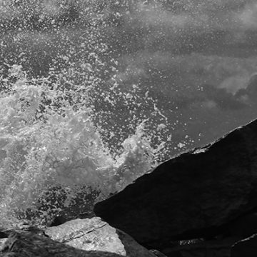 Fragmento de la fotografía de la las olas rompiendo contra una barrera de rocas