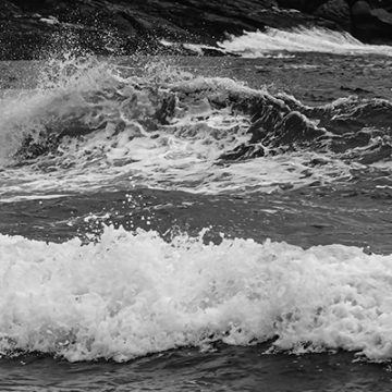 Fragmento de la fotografía de una sucesión de olas golpeando una gran roca en las costas de Brasil