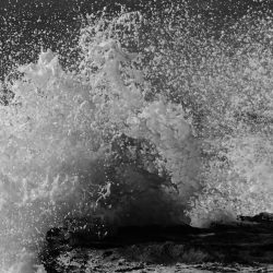 Fragmento de la Fotografía El abrazo de la colección Olas de Máximo Ruiz – Ola rompiendo contra el filo de un pequeño acantilado