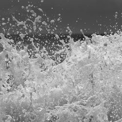 Fragmento de la Fotografía Ritmo de la colección Olas de Máximo Ruiz – La espuma y las formas creadas por una ola al romper contra las rocas